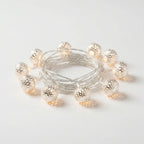 String of decorative lights with metallic bulbs on a light gray background