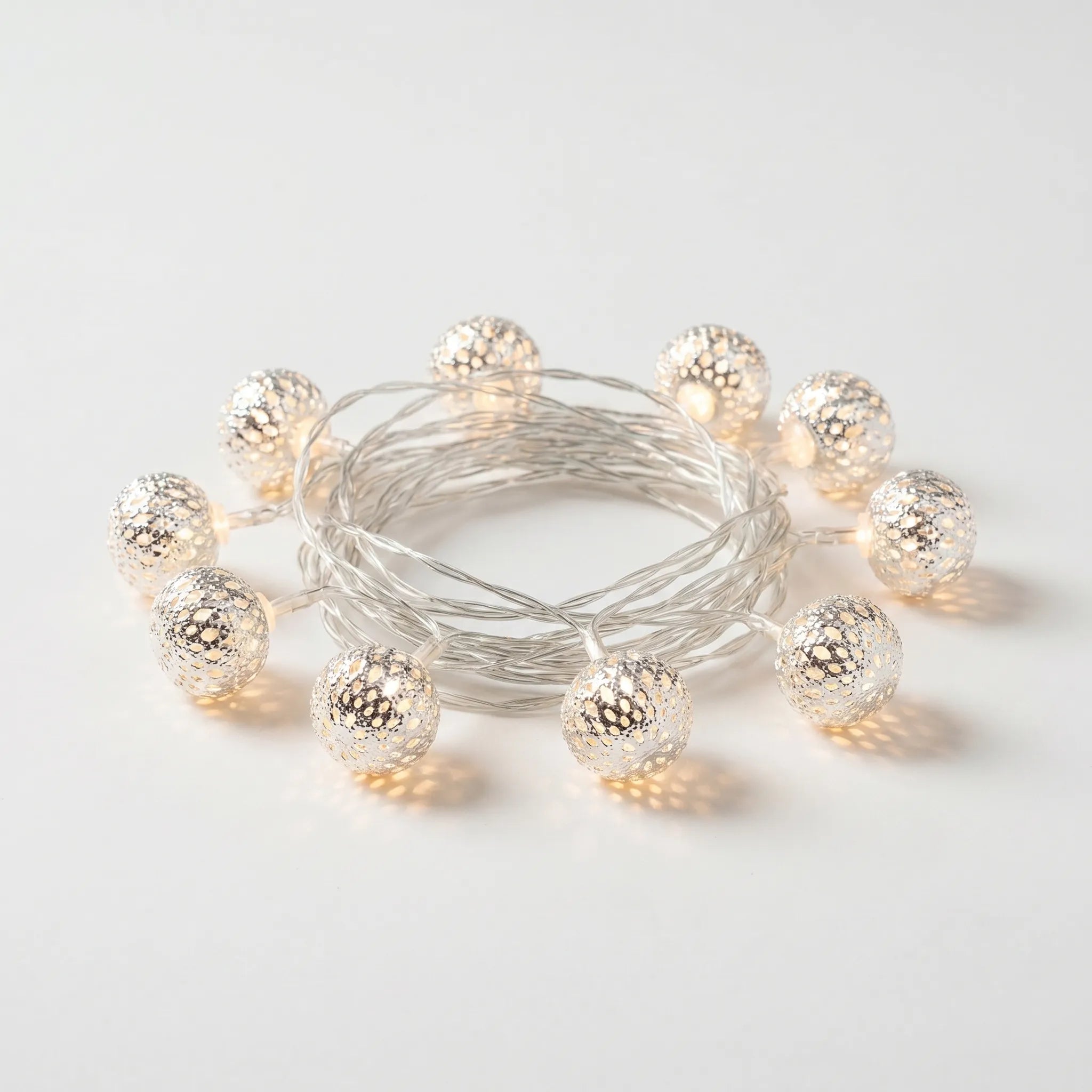 String of decorative lights with metallic bulbs on a light gray background