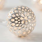 Decorative spherical lantern with intricate cut-out design on a soft background