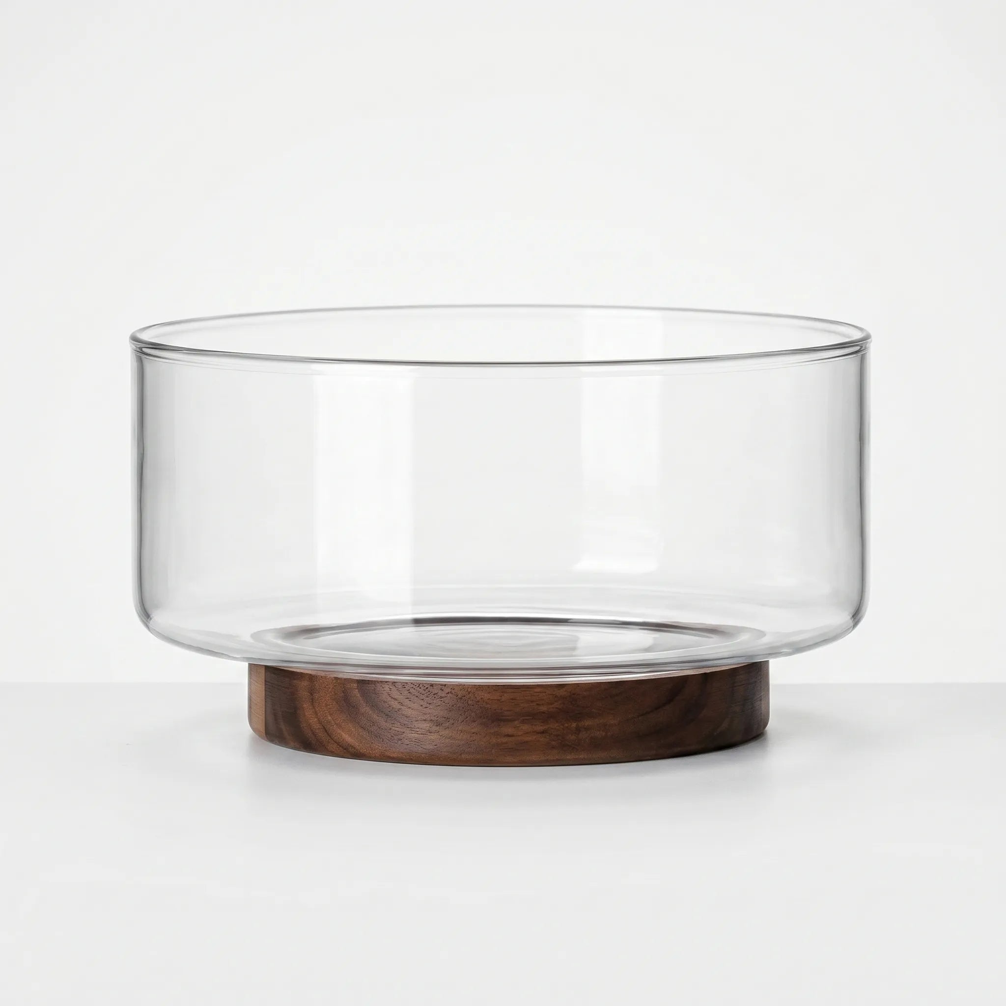 Clear Glass Serving Bowl with Walnut Wood Stand in white studio. 