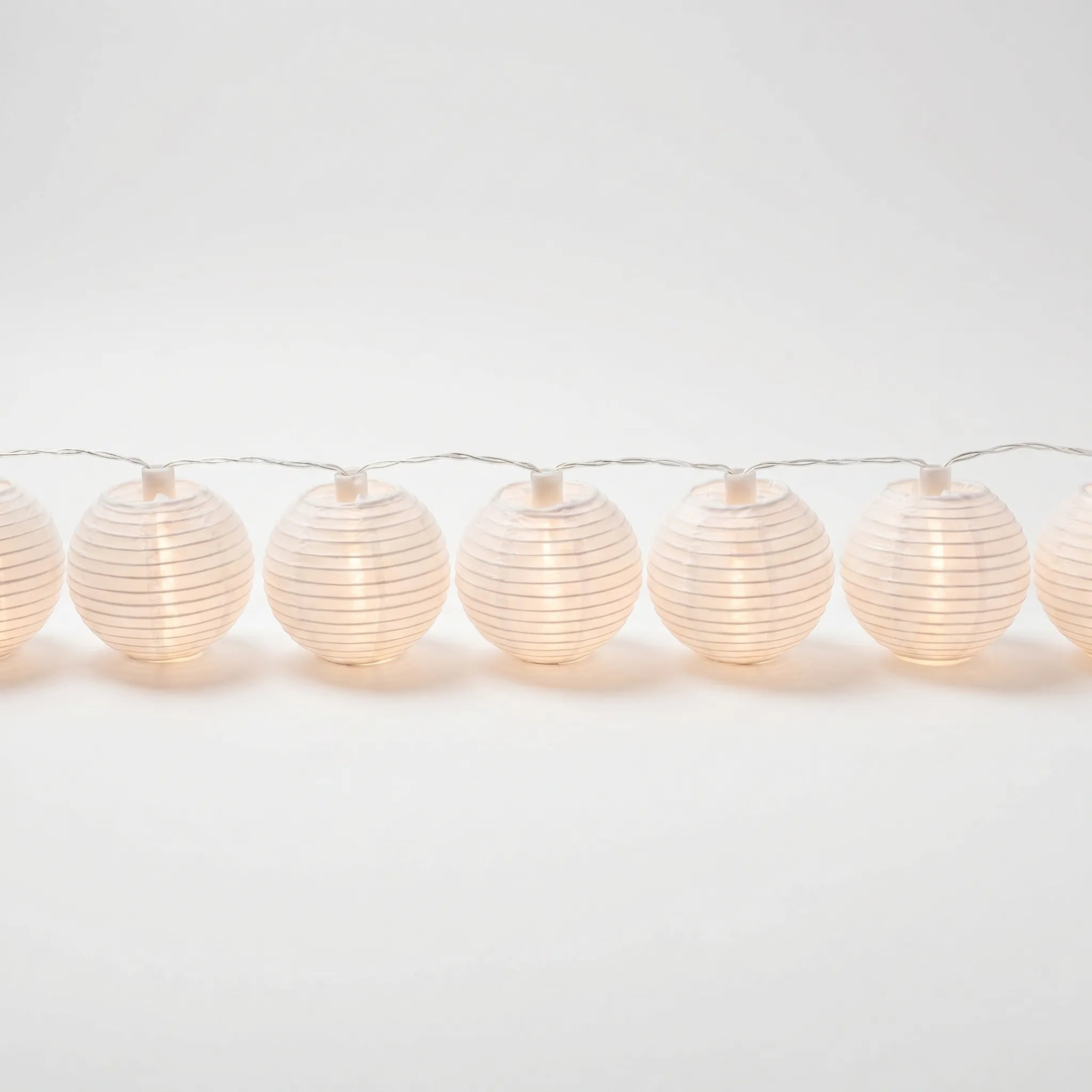 String of white paper lantern lights on a white background