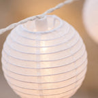 Close-up of a white paper lantern with string lights on a blurred background