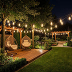 Garden setting with hanging chairs, string lights, and a wooden platform at night.
