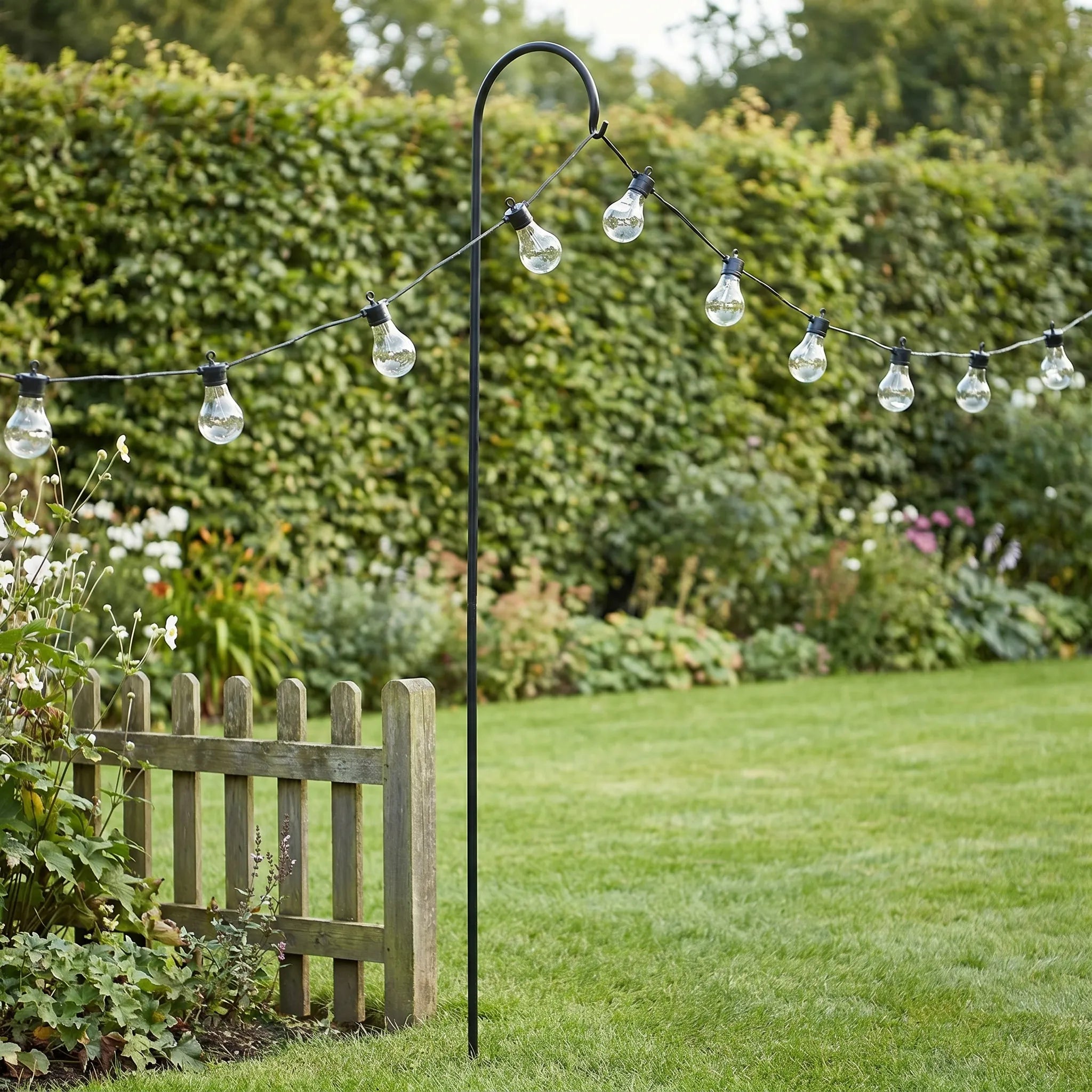 String of outdoor lights on a stand in a garden setting