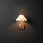 Pleated Fabric Wall Sconce – Brass Arm Wall Light with White Gathered Shade in a dark studio.
