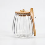Clear glass jar with wooden lid and spoon on a white background