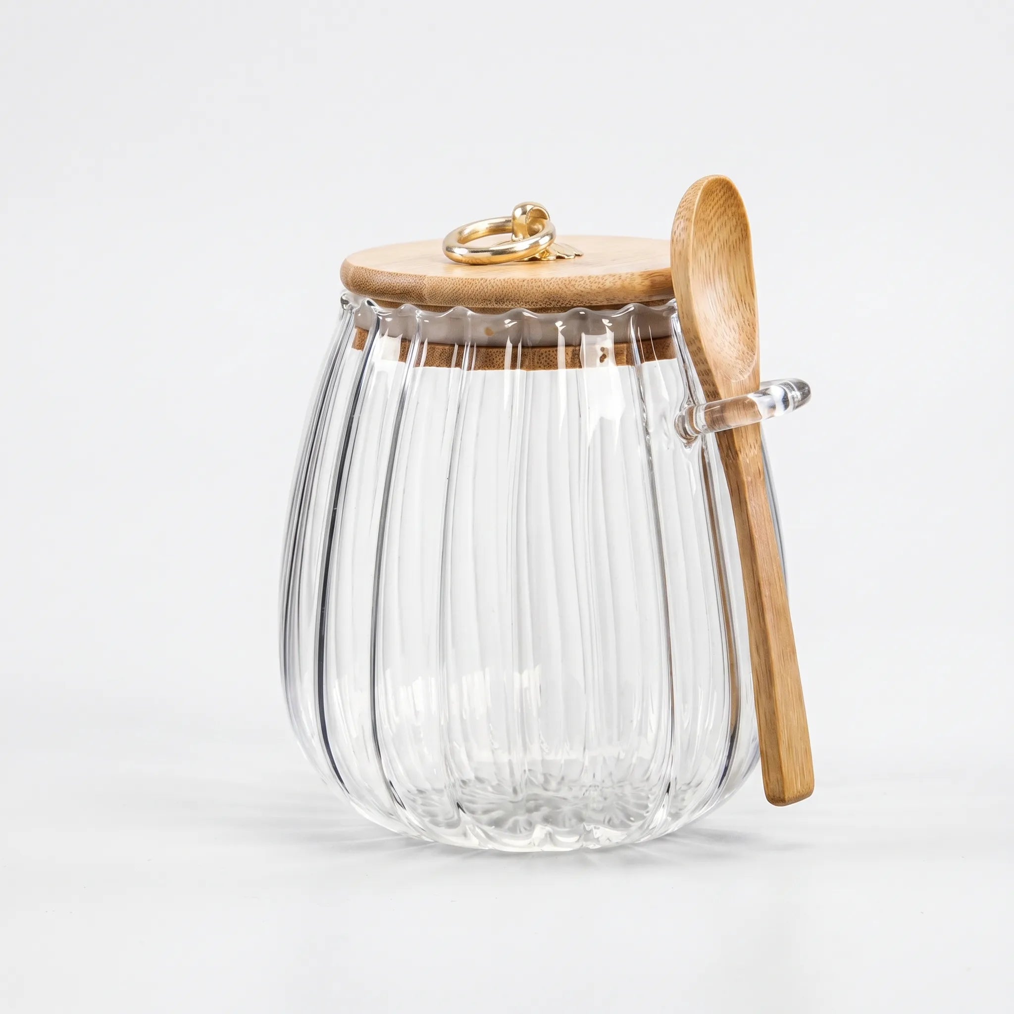Clear glass jar with wooden lid and spoon on a white background