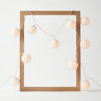Wooden picture frame with string lights on a white background