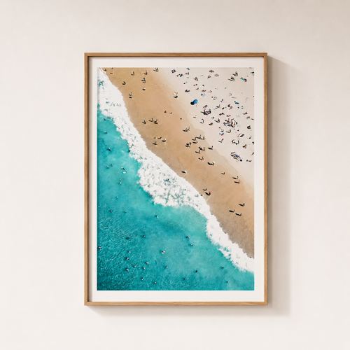 Framed artwork of a beach scene with people and turquoise water.
