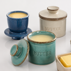 Collection of ceramic butter dishes with a block of butter on a white background