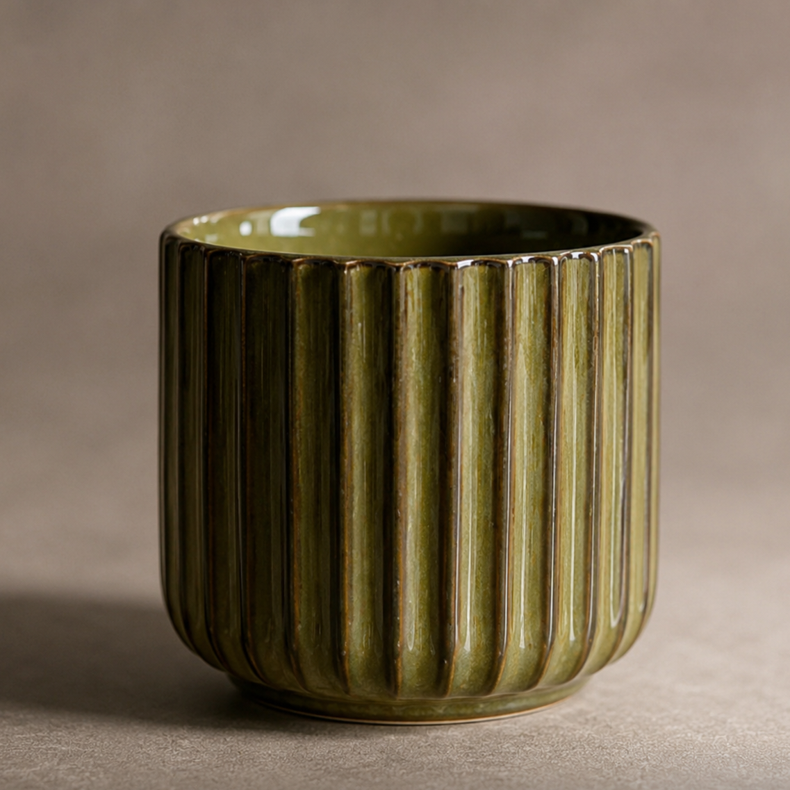 Green ceramic cup with ribbed texture on a beige background