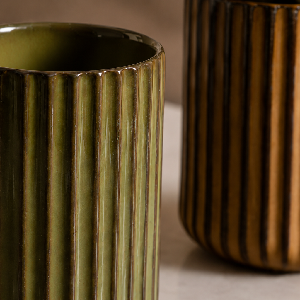 Two ceramic vases with ribbed texture, one green and one brown, on a neutral background.