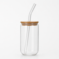 Clear glass tumbler with a wooden lid and glass straw on a white background