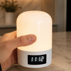 Hand holding a cylindrical night light with a digital clock display on a marble surface.