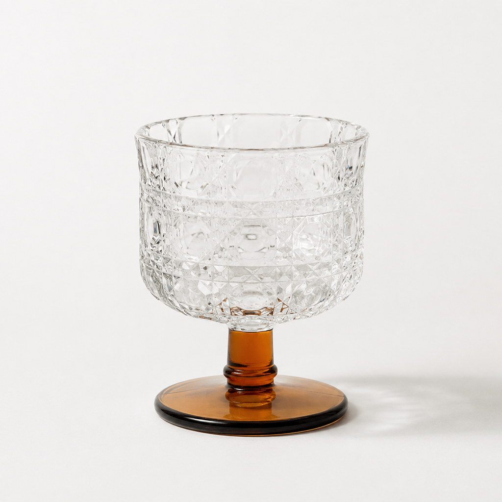 Clear glass bowl with textured surface and amber base on a white background