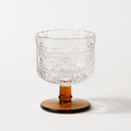 Clear glass bowl with textured surface and amber base on a white background