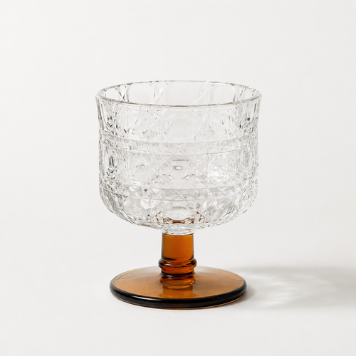 Clear glass bowl with textured surface and amber base on a white background