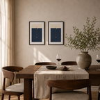 Two nice poster on the wall behind a modern dining room table.