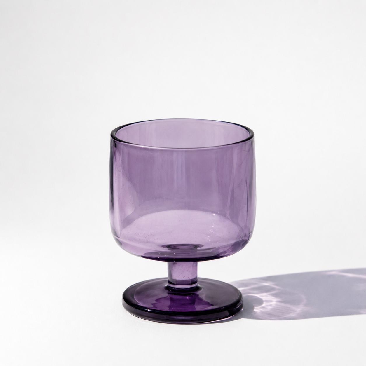 Purple glass with a stem on a white background