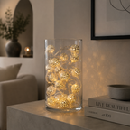 Decorative glass vase with string lights on a table in a cozy living room setting.