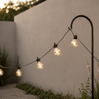 String of outdoor lights hanging from a pole against a neutral wall.