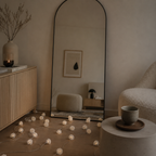 Modern interior with a tall mirror, light-colored furniture, and decorative string lights on a wooden floor.