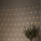 String lights arranged in a diamond pattern on a wall with two potted plants in the foreground.