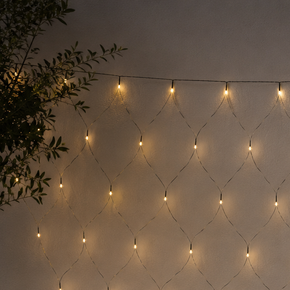 String lights arranged in a diamond pattern on a wall with plants around.