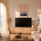 Modern living room with a television on a wooden stand, framed artwork above, and natural light coming through a window.
