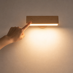 Hand pressing a wall-mounted light switch on a beige wall