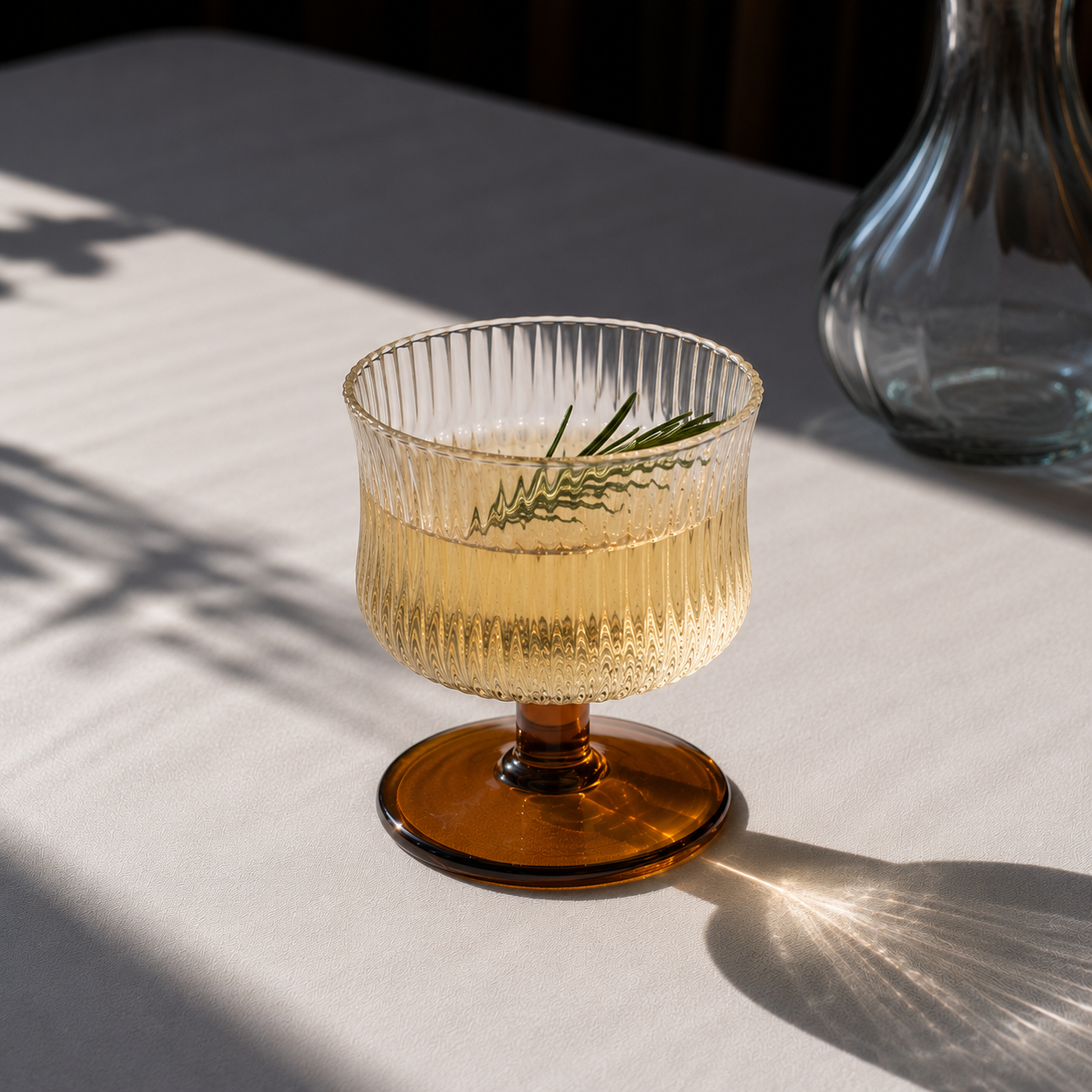 Glass with amber base and clear glass body on a light surface with a blurred background